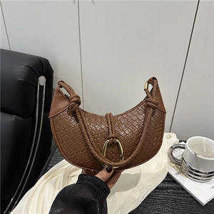Brown woven crescent bag with gold horseshoe buckle on a stylish black leather chair