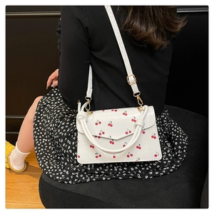 Detailed view of white cherry print square bag with gold metal buckle and PU texture