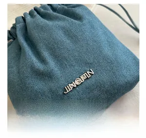 Détail de la texture en denim bleu clair et du logo métallique argenté JINGPIN