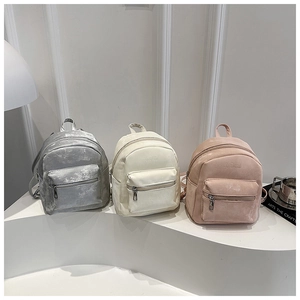 Dettaglio di mini zaini minimalisti in argento, beige e rosa con texture opaca
