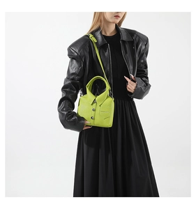 Dettaglio borsa in pelle verde neon a forma di camicia con bottoni argento e logo