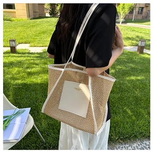 Detail of woven straw tote bag featuring white leather trim and fashion brand patch