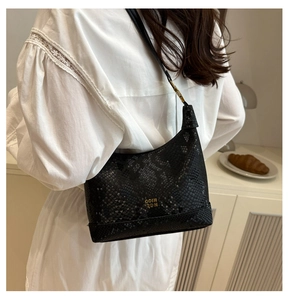 Detail of snake skin texture and gold COIN RDN logo on a black dumpling shoulder bag
