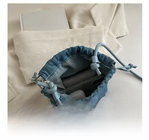 Vue intérieure du sac seau en jean bleu montrant l'espace de rangement et accessoires
