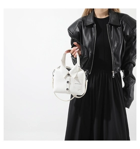 Detalle de bolso blanco con forma de camisa, botones y correa de hombro delgada