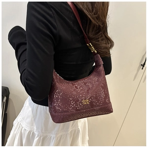 Detail of deep purple snakeskin texture on a crescent shoulder bag with gold metal logo