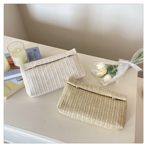 Detailed macro view of woven envelope clutch bags in beige and light brown straw texture