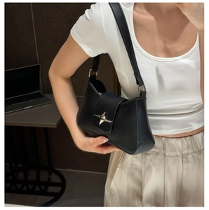 Detail shot of black minimalist shoulder bag with silver star-shaped metal buckle