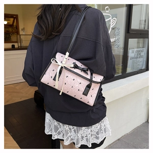 Close-up of pink embossed leather shoulder bag with bow detail and rabbit pattern