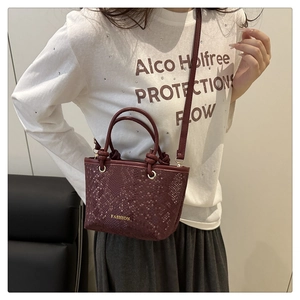 Close-up of burgundy snake-pattern mini bag with gold FASHION text and metal hardware