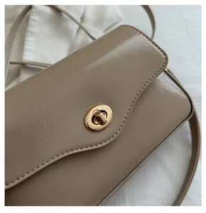 Détail du sac à bandoulière beige vintage avec fermoir rotatif en métal doré chic