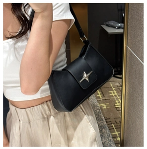 Detail of black leather shoulder bag featuring a silver star metallic buckle on a flap
