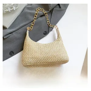 Detail of straw woven shoulder bag with gold chain handle and smartphone for size reference