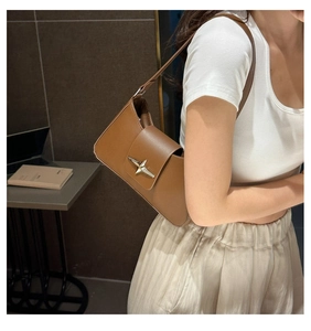 Detail of a brown leather shoulder bag featuring a silver star buckle on the flap
