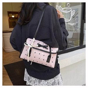 Pink pleated shoulder bag with black bunny patterns and bow detail shown on a model
