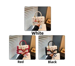 Detail of cherry print handbag with floral metal clasp and twisted rope handle