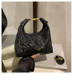 Detail of black snakeskin texture handbag with gold COIN 2DN logo and metal clasp