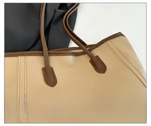 Detail view of khaki tote bag with reinforced stitching and dark brown handle