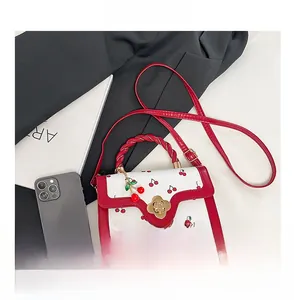 Detail view of cherry print handbag with twisted red handle and gold flower clasp
