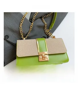 Detail of green leather and beige fabric square bag with gold chain and rotary lock
