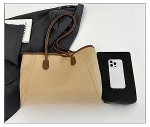 Top view of beige and brown large tote bag showing size with phone and blazer