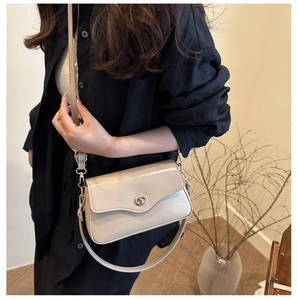 Détail du sac baguette vintage beige avec un fermoir rotatif ovale doré élégant