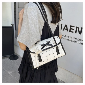 Detail of white quilted underarm bag with black bow and rabbit pattern in street style