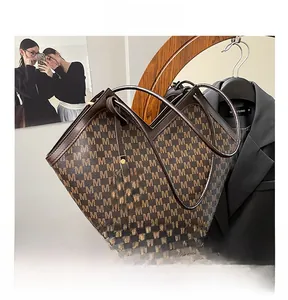 Close-up of a dark brown tote bag with all-over M pattern and gold metal pendant detail