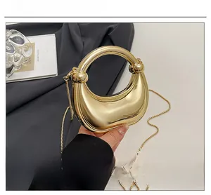 Detailed close-up of golden mirror finish crescent handbag with metallic chain strap