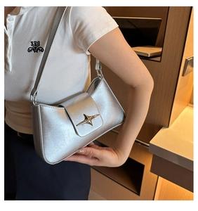 Gros plan du sac sous le bras argenté mat avec une boucle en métal doré en forme d'étoile