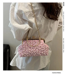 Close-up of pink floral evening clutch with 3D rose petals, pearls and gold ring handle