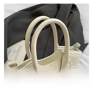 Gros plan d'un sac cabas en cuir blanc tressé avec double poignée et anneau métallique