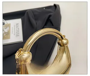 Close-up of a mini gold metallic bag with a circular handle and delicate chain strap
