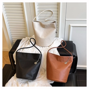 Close-up of bucket bags in beige, black, and brown with pebble grain leather texture