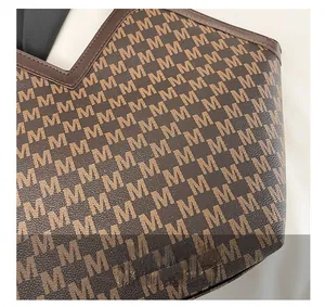 Macro view of brown monogram bucket bag showing 'M' print and high-quality leather texture