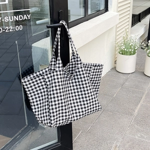 Large capacity black and white gingham canvas tote bag hanging on a minimalist door