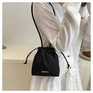 Detail of drawstring mini bucket bag with JINGPIN embroidery and slim shoulder strap
