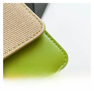 Close-up of beige woven fabric and green leather texture with fine stitching on a handbag