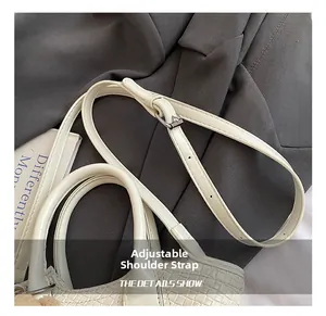 Détail de la bandoulière réglable avec boucle argentée sur le sac seau tissé de couleur beige