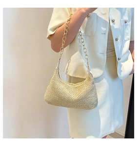 Detail of hand-woven beige straw half-moon bag with elegant chunky gold chain strap