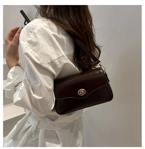 Vista lateral de mujer con bolso de hombro en cuero marrón oscuro y cierre dorado de giro