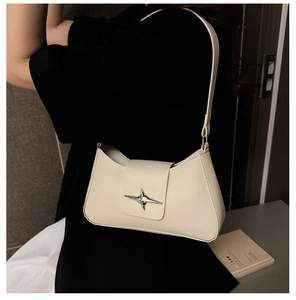 Détail du sac sous le bras blanc cassé avec boucle métallique étoile argentée sur le rabat