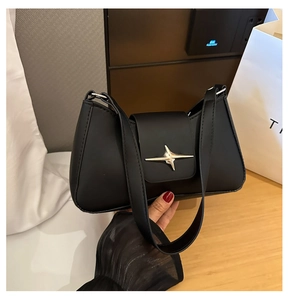 Gros plan du logo métallique en forme d'étoile argentée sur un sac baguette noir