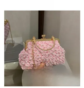 Detail of pink evening clutch bag with 3D floral roses and white pearl accents