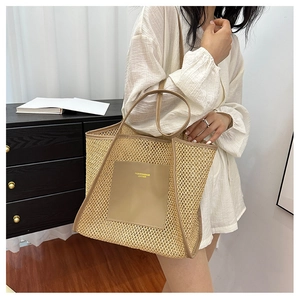 Close-up of woven tote bag with leather logo patch and long shoulder straps