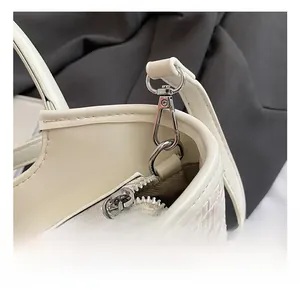 Détail de la texture en cuir tissé et finitions métalliques argentées d'un sac crème
