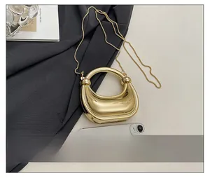 Mini gold hobo bag with mirror finish and metal chain shown next to a smartphone