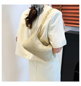 Detail of hand-woven straw shoulder bag with elegant golden chain strap for summer