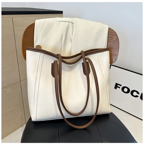 Detail of minimalist cream and brown tote bag showing smooth leather texture and long handles