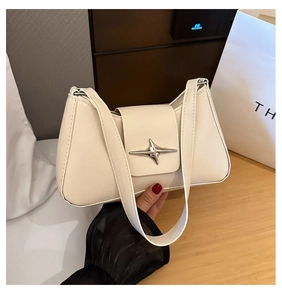 Gros plan du sac sous le bras crème avec boucle étoile argentée et cuir lisse